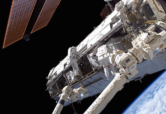 Två astronauter under en rymdpromenad vid rymdstationens horisontella fackverkskonstruktion